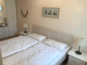 um quarto com uma cama branca e 2 candeeiros em MEI4b Ferienwohnung Landkrebs em Niendorf