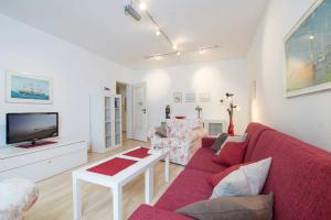 ein Wohnzimmer mit einem roten Sofa und einem TV in der Unterkunft MEI77 Ferienwohnung Zimmermann F in Niendorf