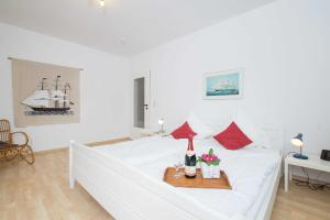ein weißes Schlafzimmer mit einem weißen Bett und roten Kissen in der Unterkunft MEI77 Ferienwohnung Zimmermann F in Niendorf