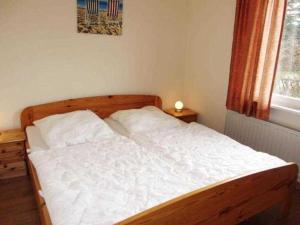 Schlafzimmer mit einem Bett mit weißer Bettwäsche und einem Fenster in der Unterkunft EIC5 Ferienhaus Schlüter in Niendorf