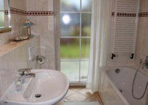 een badkamer met een wastafel, een bad en een raam bij BIR9b Ferienwohnung Vahle in Niendorf