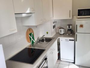 eine weiße Küche mit einer Spüle und einem Kühlschrank in der Unterkunft OST35c Ferienwohnung Sonnendeck in Niendorf