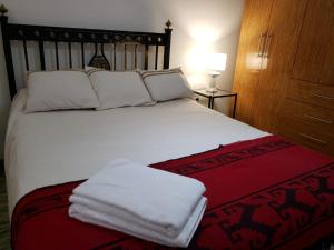 Un dormitorio con una cama con toallas blancas. en Alvarado Apart en Salta