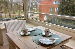 a wooden table with two plates and cups and a window at ROD32a Ferienwohnung Muschelfischer F in Niendorf +3 photos