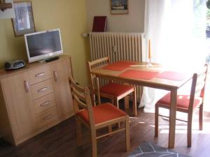 Cette chambre dispose d'une table, d'une télévision, d'une table et de chaises. dans l'établissement PAR7b "Haus Miramar" App Rothmund, à Niendorf