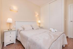 a white bedroom with a white bed and two lamps at Bhost - The King in Fuengirola