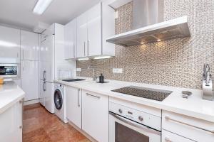 a kitchen with white cabinets and a washer and dryer at Bhost - The King in Fuengirola