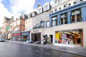 a street with shops and buildings on a city street at ALTIDO Luxury 2BR home on George Street in Edinburgh
