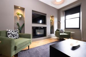 sala de estar con 2 sillas y chimenea en ALTIDO Luxury 2BR home on George Street, en Edimburgo