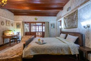 a bedroom with a large bed and a table at StayVista at Northwood Cottage with Vintage Luxury in Shimla