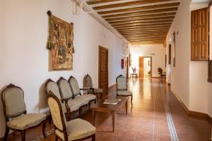 a hallway with chairs and a table and a painting on the wall at Hospederia Seminario Conciliar de San Julián in Cuenca