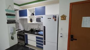 a small kitchen with a refrigerator and a microwave at Apartamento Resort Palmeiras 2 com 03 Quartos Ubatuba in Ubatuba