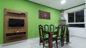 a dining room with green walls and a table and chairs at Apartamento Resort Palmeiras 2 com 03 Quartos Ubatuba in Ubatuba