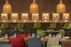 une salle à manger avec des tables et des chaises vertes dans l'établissement The Originals City, Hôtel Les Bruyères, Dax Nord (Inter-Hotel), à Castets