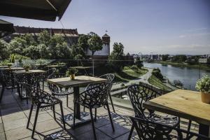 a patio with tables and chairs and a view of a river at Hotel Pod Wawelem in Krakow