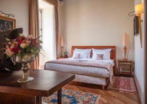 a bedroom with a bed and a table with a vase of flowers at The Pucic Palace in Dubrovnik