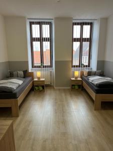 a large room with two beds and two windows at Ferienwohnung H&M Immobilien Alsleben 1 in Alsleben