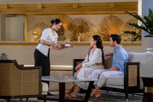 a woman presenting a plate of food to a group of people at InterContinental Bali Resort by IHG in Jimbaran