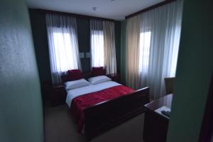a bedroom with a bed with red sheets and windows at Motel Atlantis in Prijedor