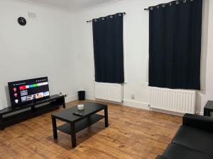 a living room with a black coffee table and a flat screen tv at Lovely 1-Bedroom Home With Free Parking & Garden. in London