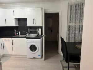 a kitchen with a washing machine next to a table at Lovely 1-Bedroom Home With Free Parking & Garden. in London