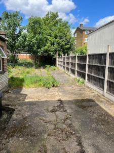 an empty yard with a fence and a building at Lovely 1-Bedroom Home With Free Parking & Garden. in London