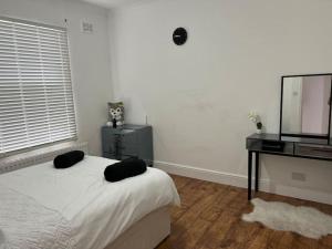 a bedroom with a bed and a desk and a television at Lovely 1-Bedroom Home With Free Parking & Garden. in London