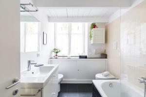 un bagno bianco con lavandino e vasca di Grifeo - Quiet and Relaxing Flat on Panoramic Route a Napoli