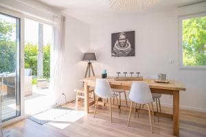 jadalnia z drewnianym stołem i białymi krzesłami w obiekcie Villa Nina- Maison cocon cosy w mieście La Teste-de-Buch