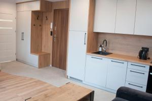a kitchen with white cabinets and a wooden floor at Apartament BURSZTYN in Darłówko