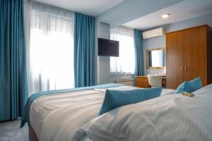 - 2 lits dans une chambre d'hôtel dotée de rideaux bleus dans l'établissement Hotel Villa Harmony, à Sarajevo
