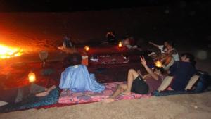 a group of people sitting on the beach at night at Erg Chegaga Desert Night in El Gouera