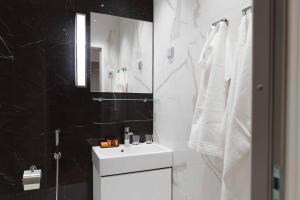 Baño en blanco y negro con lavabo y espejo en Hotel Bastian en Helsinki
