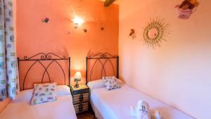 two beds in a room with orange walls at Casa Rural La Higuera El Gastor by Ruralidays in El Gastor +15 photos