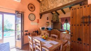 a kitchen and dining room with a table and a clock on the wall at Casa Rural La Higuera El Gastor by Ruralidays in El Gastor