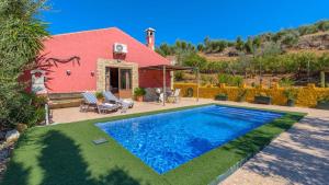 a swimming pool in front of a red house at Casa Rural La Higuera El Gastor by Ruralidays in El Gastor