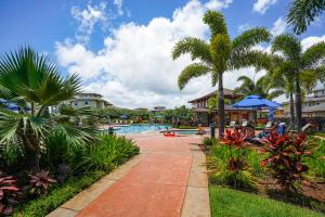 a pool at a resort with palm trees and people swimming at Pili Mai 1L in Koloa