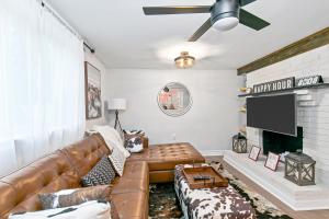 a living room with a brown leather couch and a tv at East Nashville Nook Best of Both Worlds in Nashville