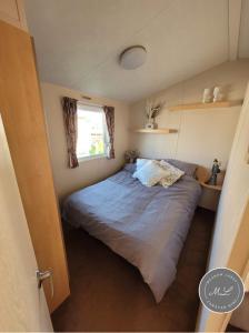ein Schlafzimmer mit einem Bett in einem kleinen Zimmer in der Unterkunft Meadow View 81 - Golden Palm, Central Heating, WiFi, pet friendly - Meadow Lakes Caravan & Lodge Hire in Chapel Saint Leonards + 8 Fotos