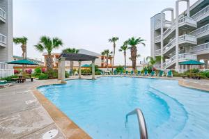 a large swimming pool at a resort with palm trees at Casa Del Mar Skip to the Beach 294 in Galveston