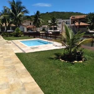 una piscina en un patio con una palmera en Casa temporada., en Cabo Frío