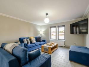 a living room with blue couches and a tv at Westertonhill Lodge 3 with Hot Tub Option in Balloch