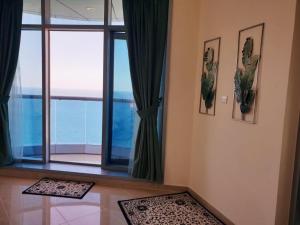 Zimmer mit einem großen Fenster und Meerblick in der Unterkunft LUXURIOUS SEA VIEW APARTMENT FOR STAYS! in Ajman 