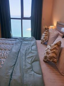 a bed in a bedroom with a large window at LUXURIOUS SEA VIEW APARTMENT FOR STAYS! in Ajman 
