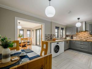 uma cozinha em plano aberto e uma sala de jantar com uma mesa e uma máquina de lavar roupa em Westertonhill Lodge 8 Newbuild with Hot Tub Option em Balloch