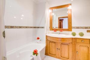 ein Badezimmer mit einer weißen Badewanne, einem Waschbecken und einem Spiegel in der Unterkunft Ideal Property Mallorca - Sa Dalia in Port d'Alcúdia + 25 Fotos