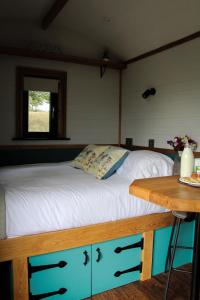 a bed in a room with a wooden table at Cwm Cariad in Knighton