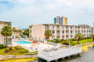 an apartment building with a dock in front of a body of water at Beach Cottage at OD in Myrtle Beach