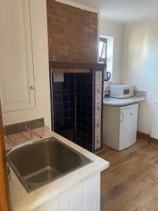 a kitchen with a sink and a brick wall at Bean Farm House Apartment in Stonewood
