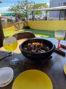 a table with a bowl of food and two glasses of wine at Casa da Rô !!! Melhor casa frente ao mar de Ubu !!! in Anchieta
